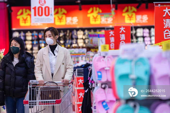 戴口罩的青年女人在超市购物