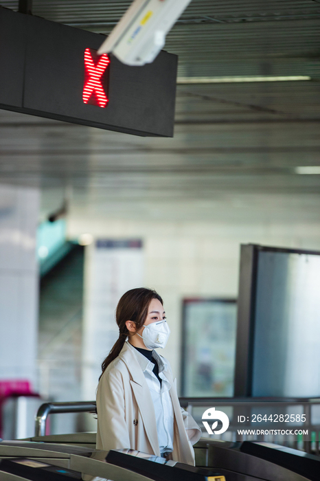 戴口罩的年轻女人走进地铁站