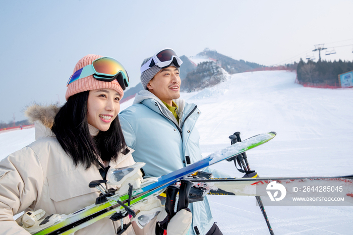雪场上拿着滑雪板滑雪杖的快乐情侣