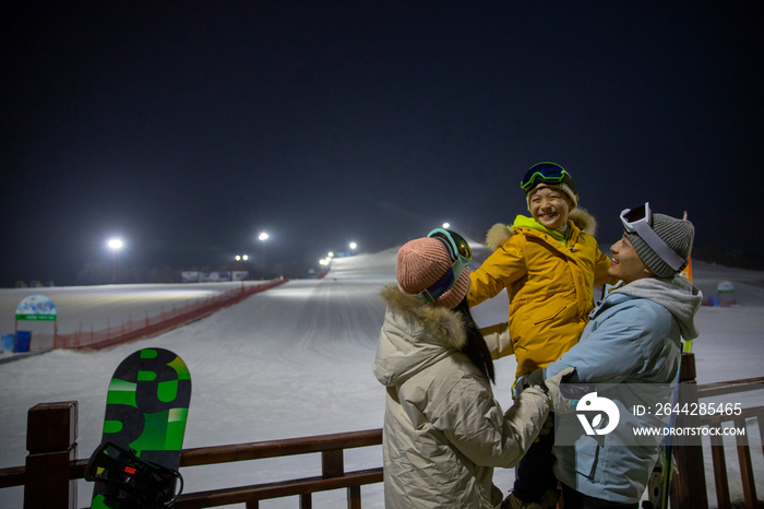 夜景下的滑雪场内的一家三口