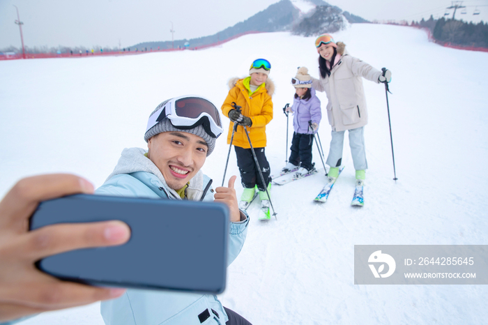 滑雪场上用手机自拍的一家四口