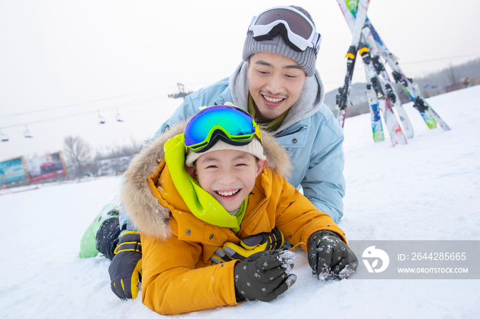 滑雪场内抱在一起打滚的快乐父子