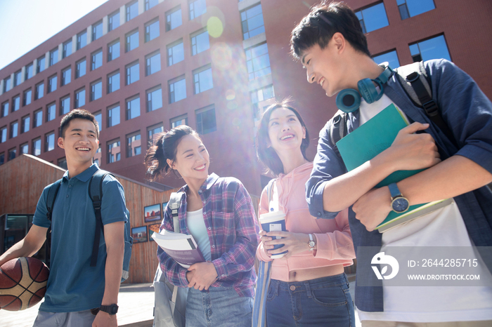 阳光下四个大学生在校园里边走边聊