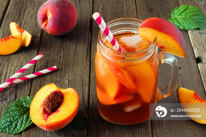 Fresh peach iced tea in a mason jar glass. Table scene with a rustic dark wood background.