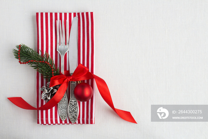 Christmas table setting on the striped napkin the on the white textile background. Top view. Copy space.