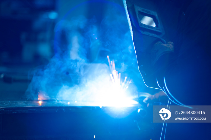 Machine manufacturing in the workshop. Metal joining by welding. Source light and effect. Skilled worker using welding machine.