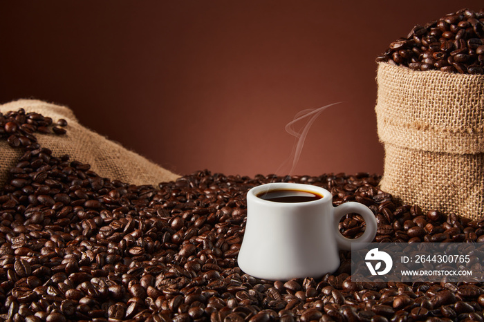 White cup with coffee beans on dark background