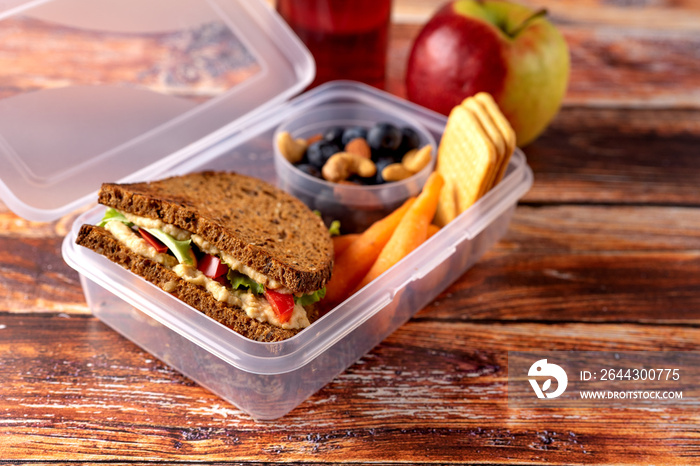 Close up of school lunch box with vegan sandwich, nuts and berries