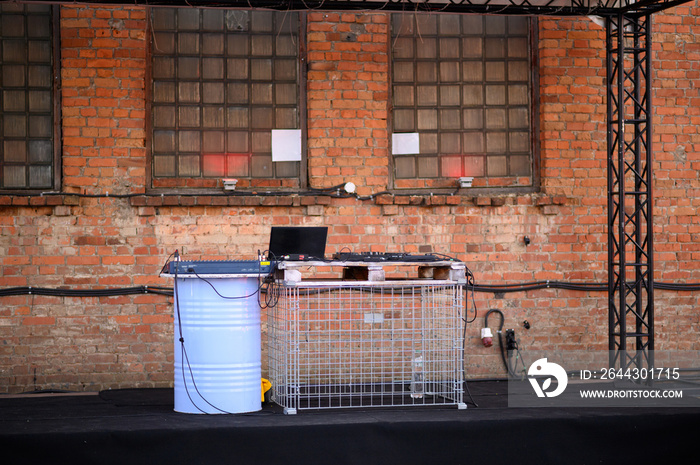 Empty DJ booth against a brick wall. Party at a closed factory