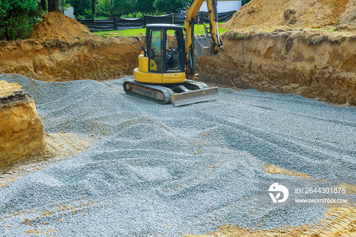 Excavator digging bucket scooping gravel from a building foundation