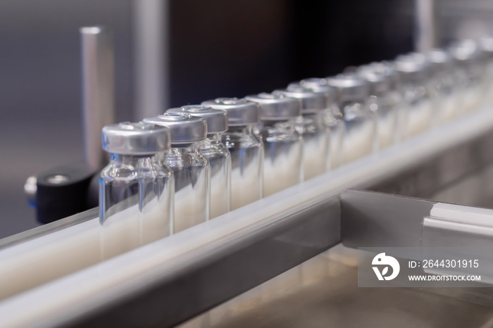 Conveyor belt with empty medical injection glass vials - pharmaceutical automatic production line. Pharmaceutical industry, manufacturing, medicine and automated pharma technology equipment concept