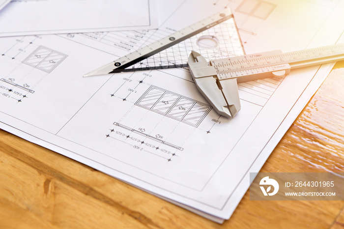 Close up of caliper with architect sketching a construction project