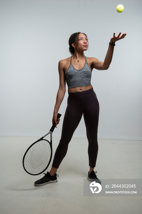 Woman holding tennis racket and throwing tennis ball