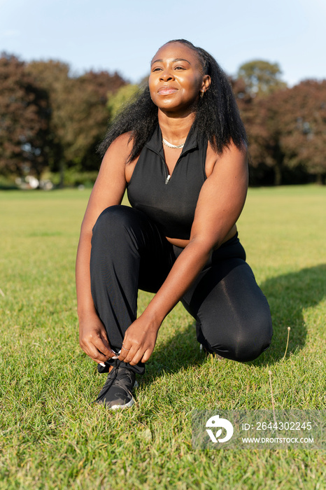 Young woman tying shoes before exercising in park