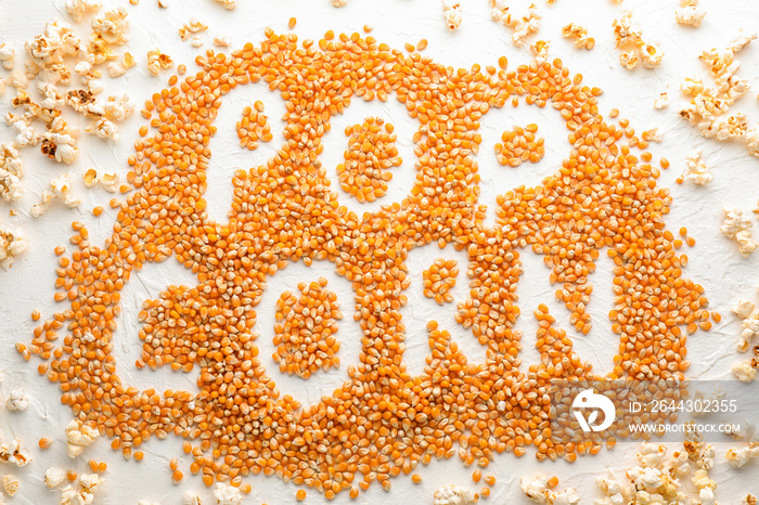 Delicious popcorn and words made of kernels on white table