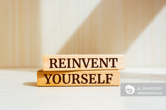 Wooden blocks with words ’REINVENT YOURSELF’.