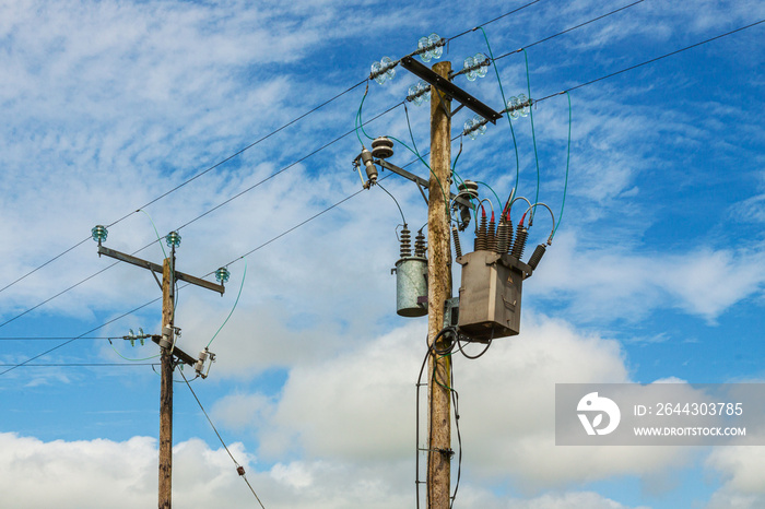 Power line with wooden poles on a green field