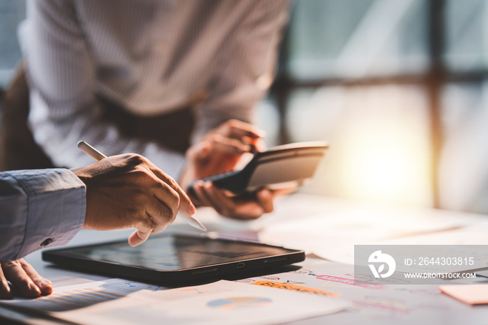 Young colleagues discuss business and analytical price charts using calculators and laptops to calculate financial, tax, accounting, statistics and analytical research ideas.