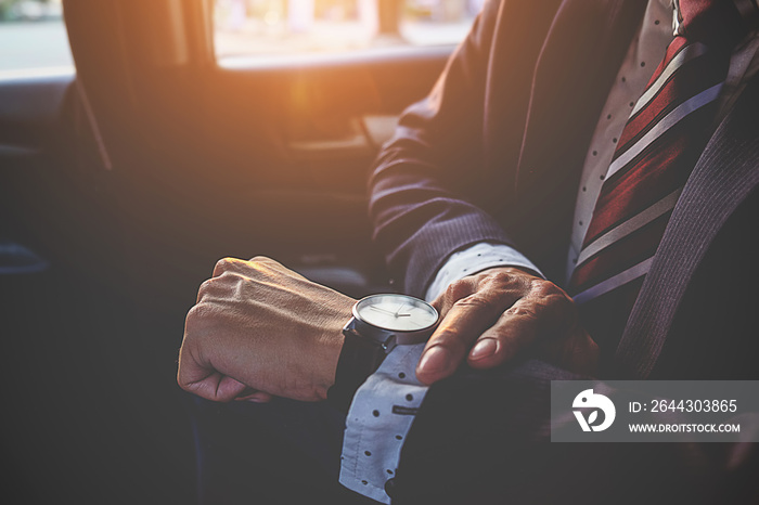 Businessman looking at the time on his wrist watch in car. Business concept.