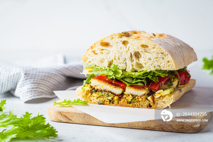 Vegetarian sandwich with grilled vegetables, halloumi cheese and ciabatta on board, white background. Comfort food concept.