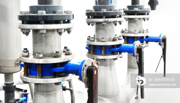 Large industrial water treatment and boiler room. A row of manual butterfly valves, flanges with rusty and corroded bolts