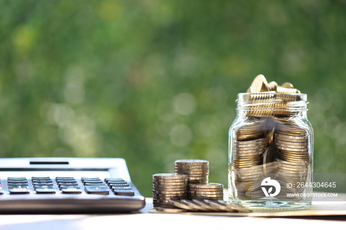 Finance, Coin money in the glass bottle with calculator on natural green background, Save money for prepare in future and pension retirement concept