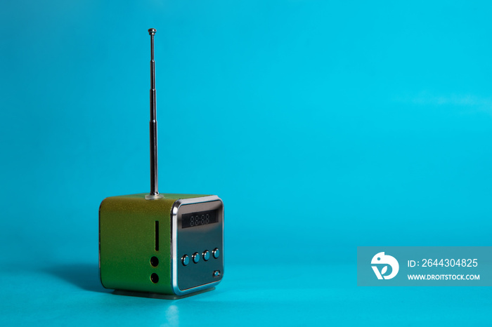 Small green radio on a blue background. The concept of listening to music, listening to the radio.