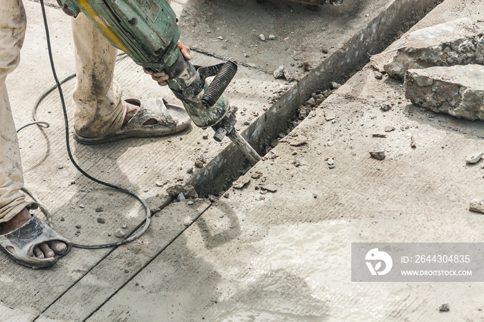 Construction worker using jackhammer drilling concrete surface