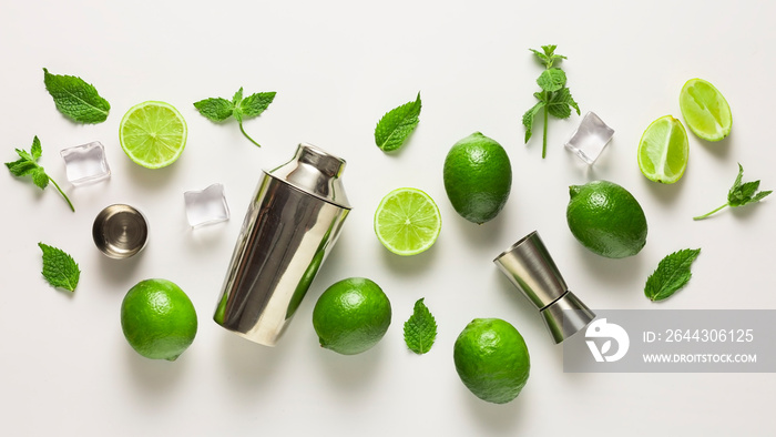 Mojito lime set, flat lay on white background. Concept: Mojito Cocktail. Whole juicy limes with ice and cocktail shaker. Concept: summer refreshing cocktail.