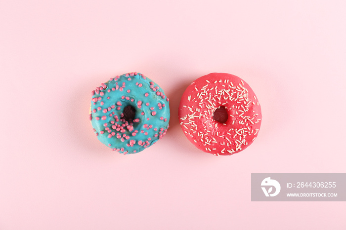 Top view composition of lush donut with colorful sprinkled icing, on bright paper textured background with a lot of copy space for text. Tasty but unhealthy food concept. Close up, flat lay, frame.