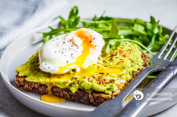 Avocado toast with poached egg on gray plate. Vegetarian healthy food concept.