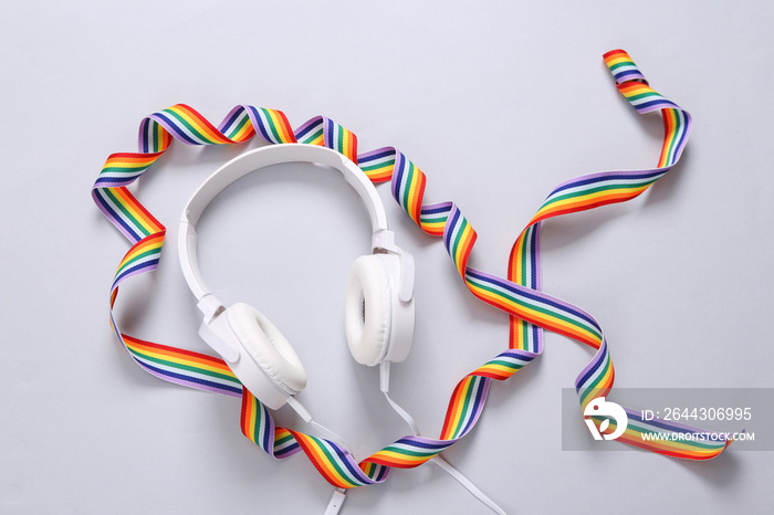 Stereo headphones with rainbow ribbon on gray background. LGBT community. Top view