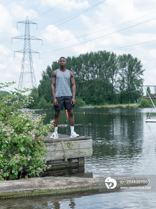 Muscular man in sports clothing standing by lake