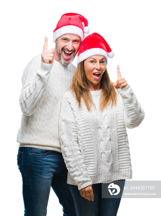 Middle age hispanic couple wearing christmas hat over isolated background pointing finger up with successful idea. Exited and happy. Number one.