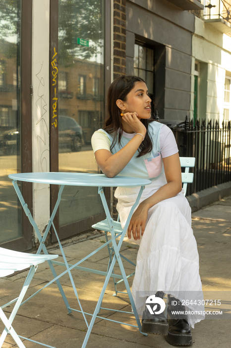 Young woman sitting in sidewalk cafe