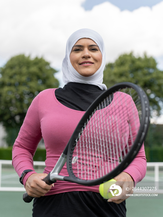 UK,Sutton,Portrait of smiling woman in headscarf at tennis court