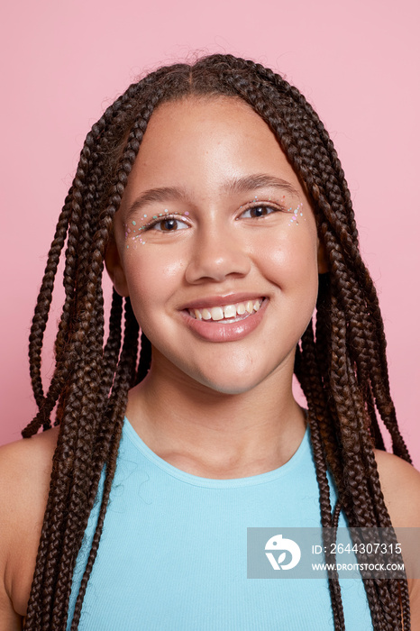 Studio portrait of smiling girl with braids and decorative stickers on face