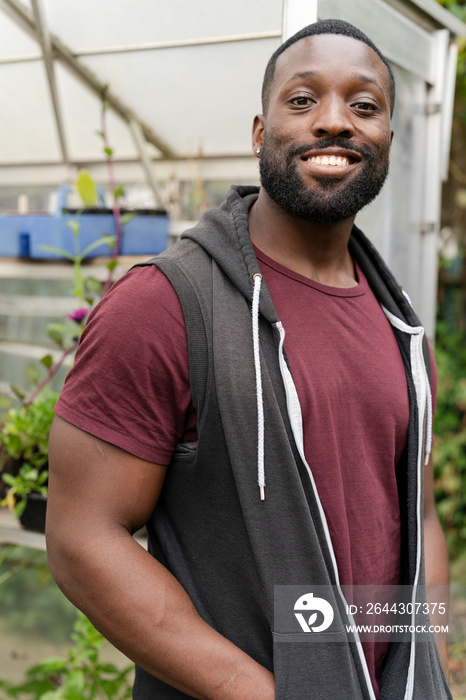 Portrait of smiling man standing in front of greenhouse