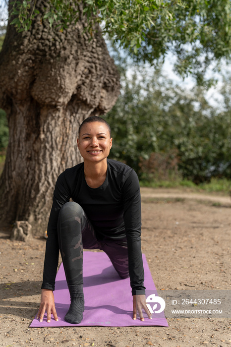 Portrait of smiling woman in low lunge pose in park