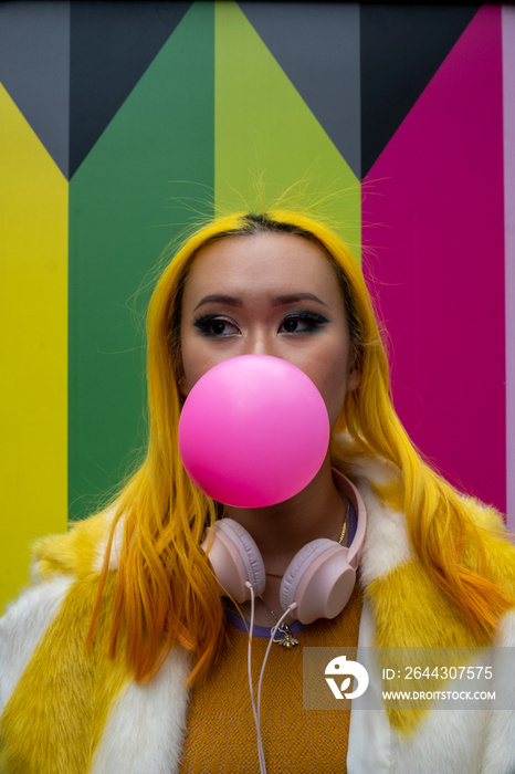 Young woman with yellow hair blowing bubble gum