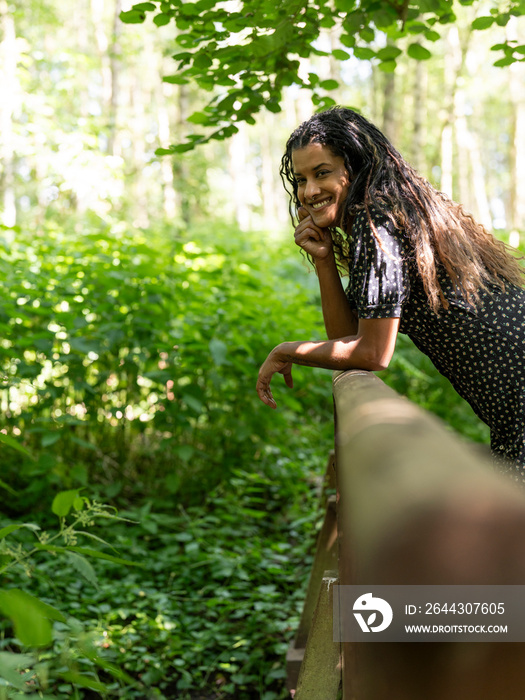 Portrait of woman leaning on railing in forest