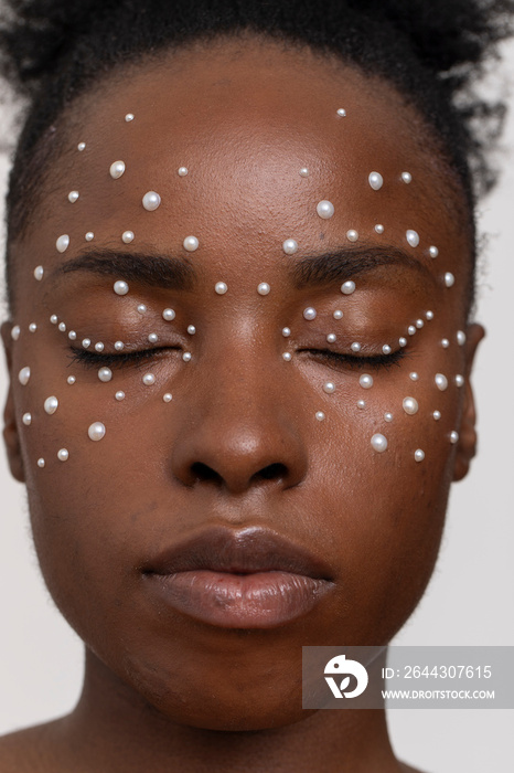 Young woman with closed eyes, wearing pearl freckles