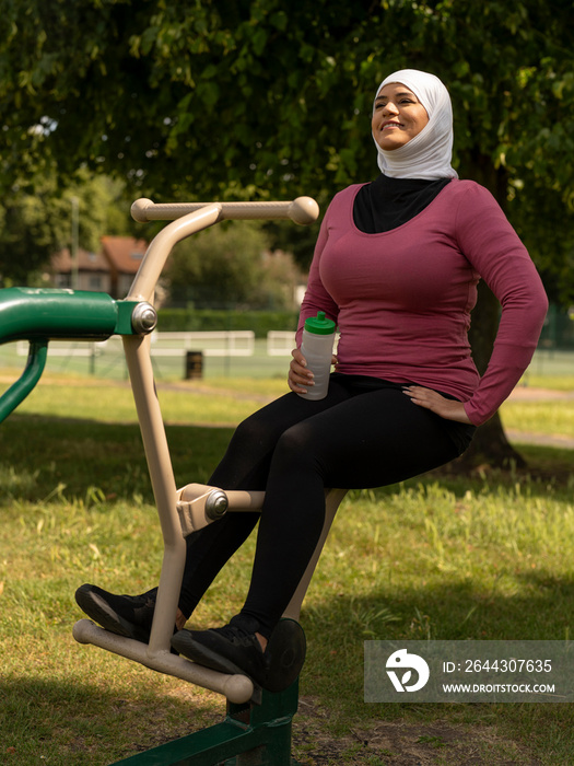 UK,Sutton,Smiling woman in headscarf exercising at park gym