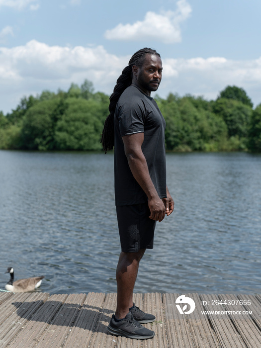 Muscular man in sports clothing standing by lake