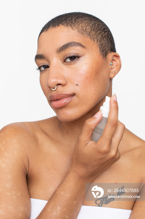 Studio portrait of woman applying face serum