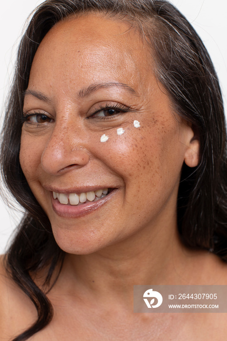 Studio portrait of smiling woman with dots of eye cream