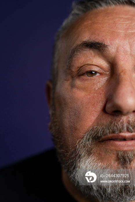 Portrait of serious man with beard against purple background