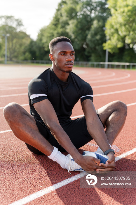 Athlete stretching legs before training at sports track