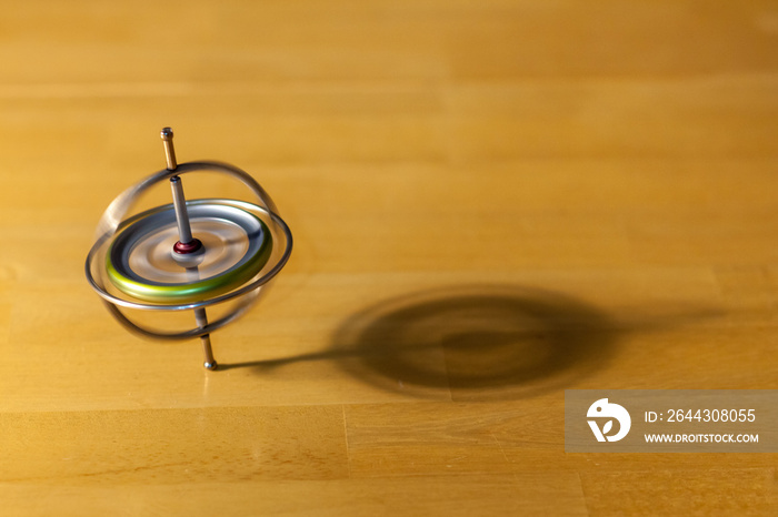 Toy gyroscope spinning and balancing on a wooden table