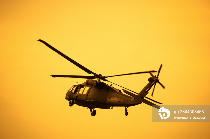 Silhouette of the military helicopter  moving into sky at sunset